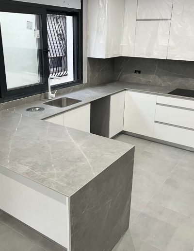 Cocina en U con encimera y frentes de porcelánico gris efecto piedra