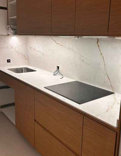 Encimera de porcelánico blanco con panel a juego y placa de inducción integrada