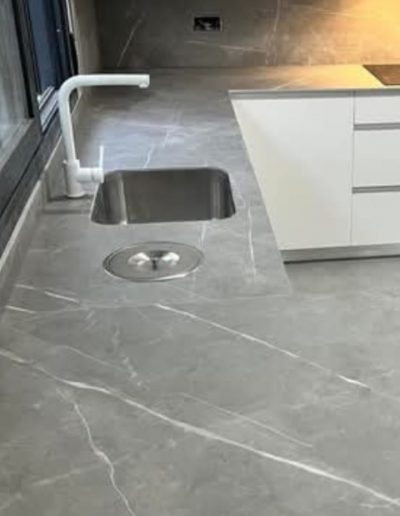 Encimera de porcelánico gris con fregadero bajo encimera y grifo blanco