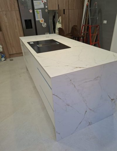 Isla de cocina con encimera de porcelánico blanco efecto mármol y frente en cascada